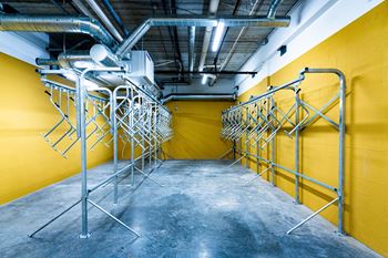 A room with yellow walls and a concrete floor has a metal rack system.